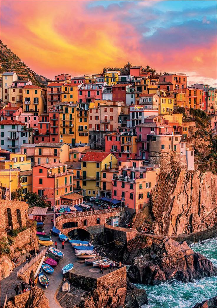 The colourful cliffside village of Manarola in the Cinque Terre, reflected in the Ligurian Sea at golden hour