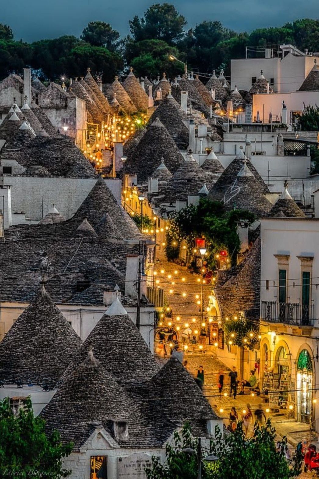 The UNESCO trulli of Alberobello at dusk — the cone-shaped limestone rooftops of the Valle d'Itria glowing in the last light